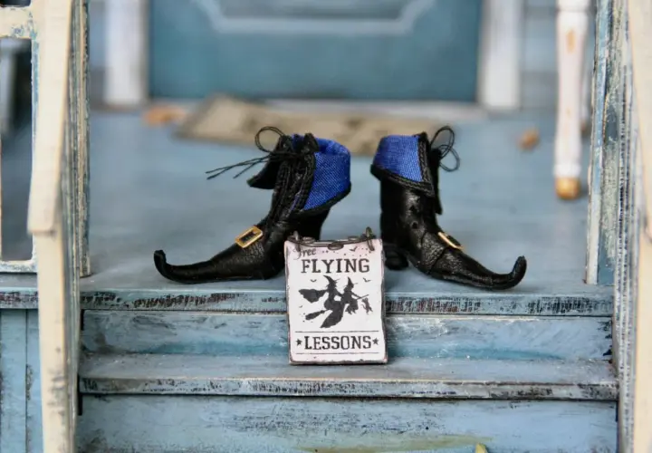 Stivaletti da strega neri con un cartello "Free Flying Lessons" per le parole di Halloween.