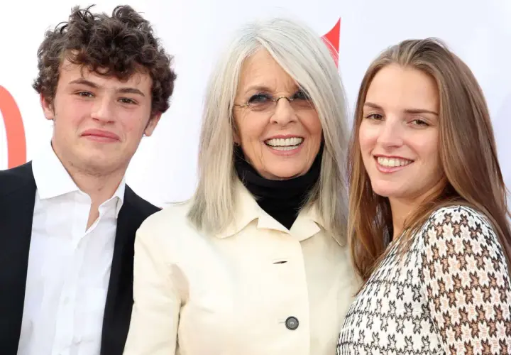 Diane Keaton z uśmiechem pozuje z dwójką swoich dzieci, synem i córką, na czerwonym dywanie.