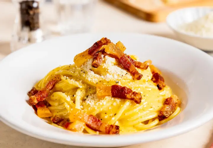 Ein Teller mit authentischer Spaghetti Carbonara, garniert mit knusprigem Guanciale und Pecorino. Ein wahrer Genuss der italienischen Küche.