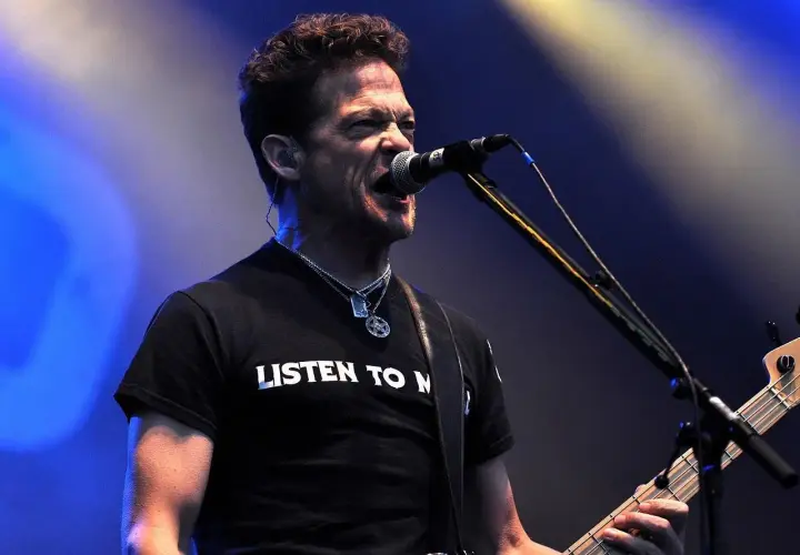 Jason Newsted z zespołu, w czarnej koszulce z napisem "LISTEN TO N", śpiewa do mikrofonu, grając na basie.