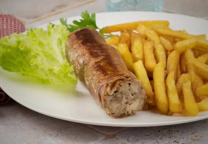 Une belle andouillette grillée avec des frites croustillantes et une feuille de laitue fraîche. Un plat simple et savoureux.