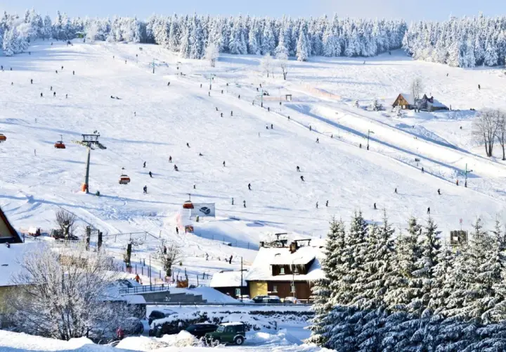 Stok narciarski w Karkonoszach, idealne miejsce na ferie zimowe 2026 dolnośląskie. Narciarze szusują, kolejki wywożą na szczyt.