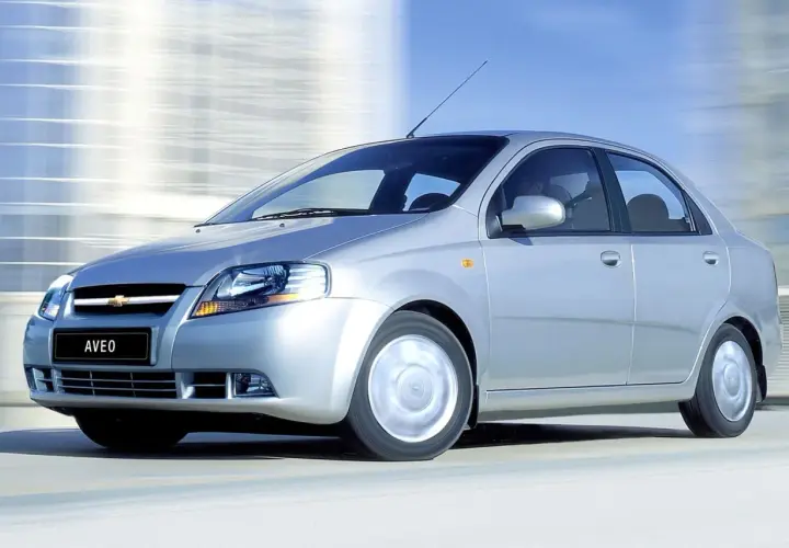 Srebrny Chevrolet Kalos, model Aveo, pędzi po drodze, rozmywając tło.