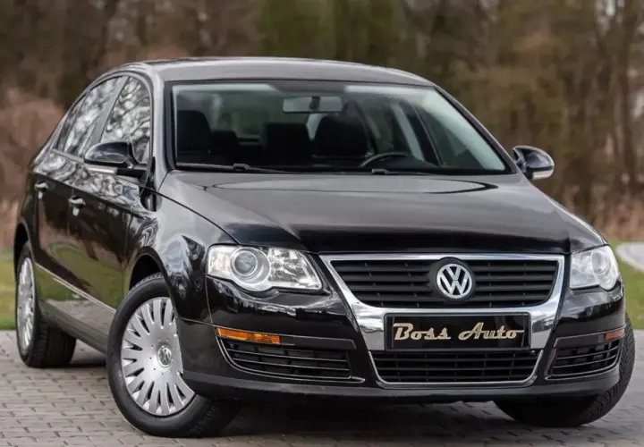 Czarny Volkswagen Passat B6 na tle drzew. Elegancki, lśniący lakier i chromowane detale podkreślają jego klasę.