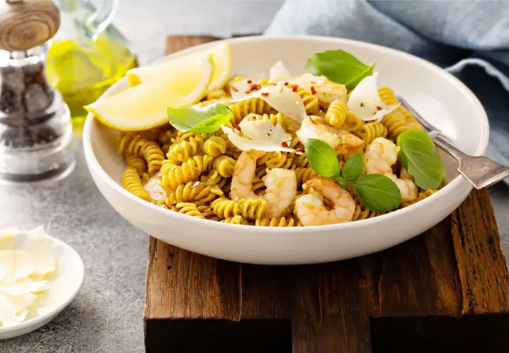 Pyszny makaron z ciecierzycy z krewetkami, cytryną i parmezanem, udekorowany bazylią.