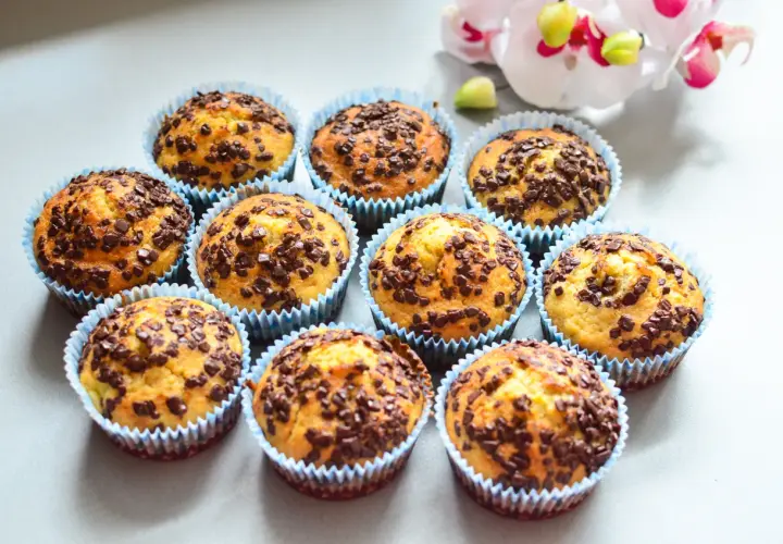 Urocze muffinki bananowe z czekoladą, posypane obficie czekoladowymi drobinkami, wyglądają apetycznie.