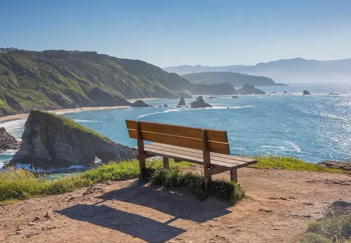Un banco de madera invita a contemplar el mar azul y las verdes colinas. Podría ser el banco mas bonito del mundo en Vigo.
