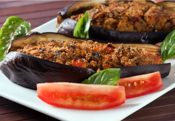 Melanzane ripiene al forno velocissime, dorate e gustose, servite con pomodoro fresco e basilico.
