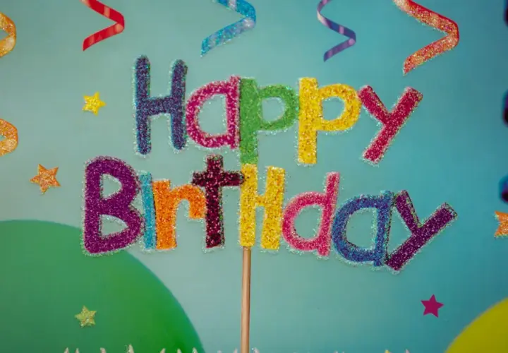 Kolorowe, brokatowe życzenia urodzinowe po angielsku "Happy Birthday" na tle serpentyn i gwiazdek.