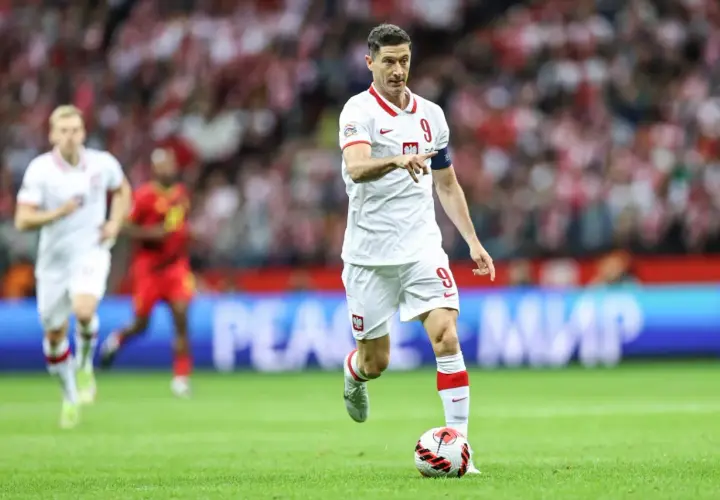 Robert Lewandowski, polska fałszywa dziewiątka, prowadzi piłkę na boisku w białej koszulce z numerem 9.