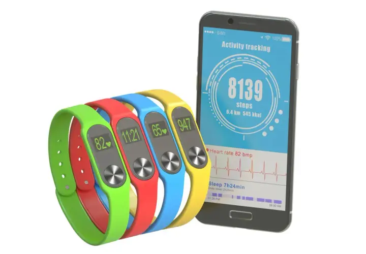 Kolorowe opaski monitorujące aktywność i smartfon z aplikacją do liczenia kroków.