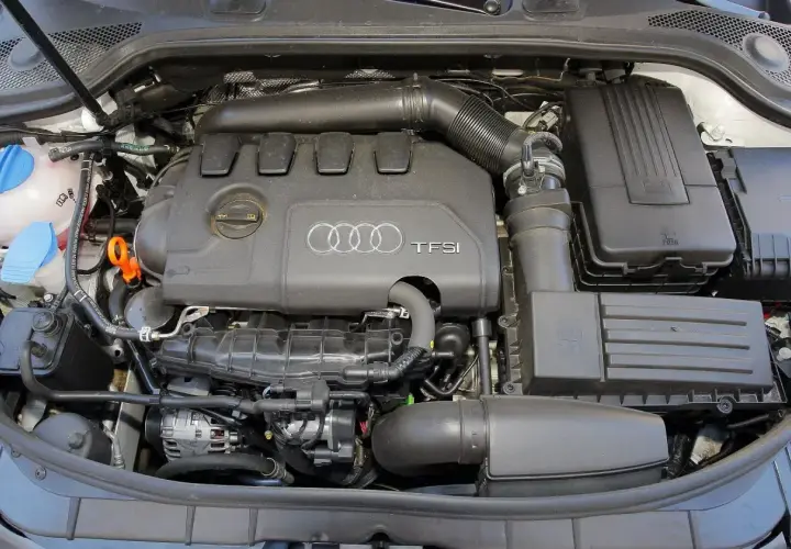 Silnik TFSI w Audi 8P, widok z góry. Widać pokrywę silnika z logo Audi, elementy układu dolotowego i filtry.