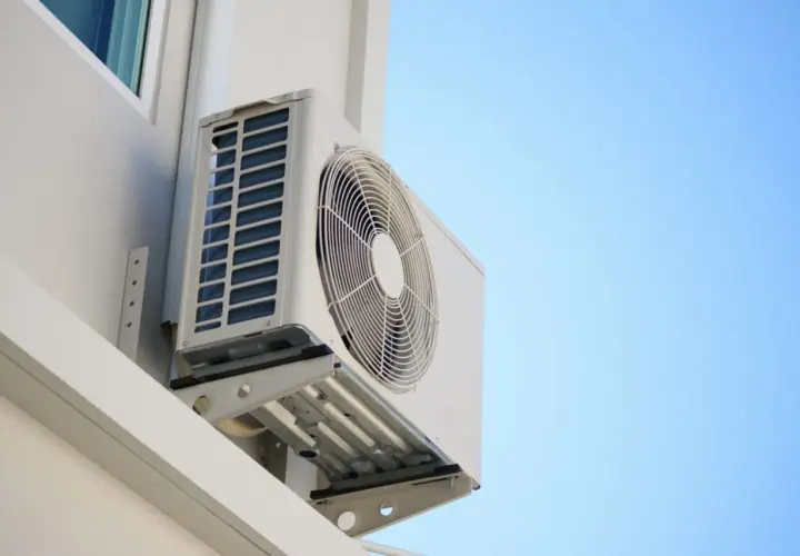 Unidad exterior de aire acondicionado montada en pared blanca, ideal para saber donde colocar la unidad exterior del aire acondicionado para una óptima ventilación.