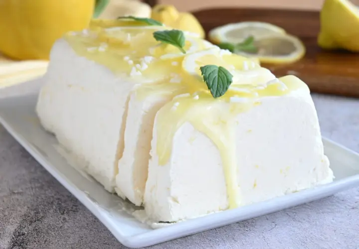 Un delizioso semifreddo al limone, guarnito con scorzette, menta e una glassa gialla. Perfetto per un dessert rinfrescante.