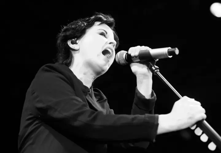 Dolores O'Riordan, jedna z członkiń The Cranberries, śpiewa do mikrofonu z pasją.