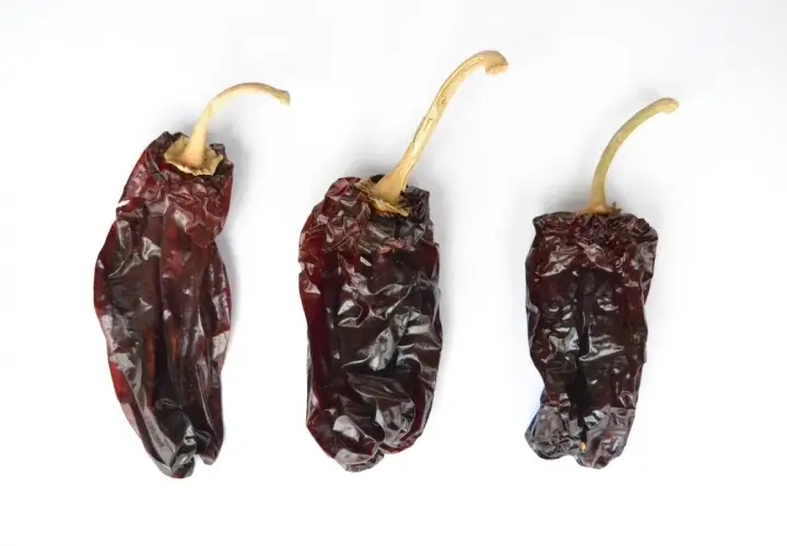 Tres pimientos choriceros secos, oscuros y arrugados, listos para dar sabor a guisos y salsas.