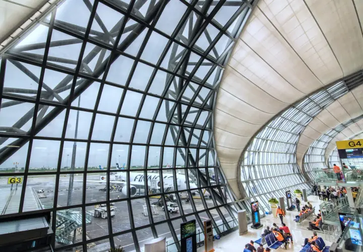 Moderne Architektur am Flughafen Bangkok: Flugzeuge stehen bereit, während Reisende im Wartebereich auf ihren Abflug warten.