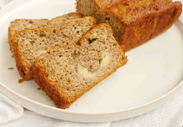 En saftig banankaka i långpanna, skuren i skivor och serverad på en vit tallrik. Perfekt för fikat!