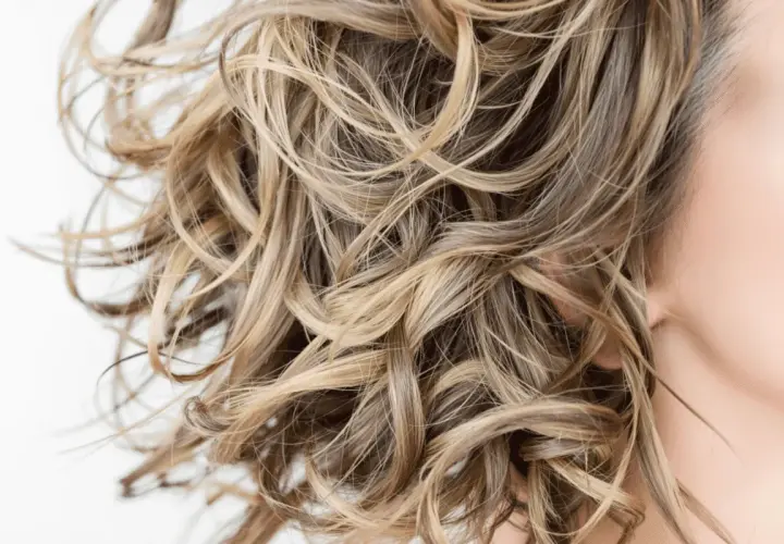 Cabello rubio ondulado y sedoso, libre de sulfatos y parabenos, con reflejos dorados.