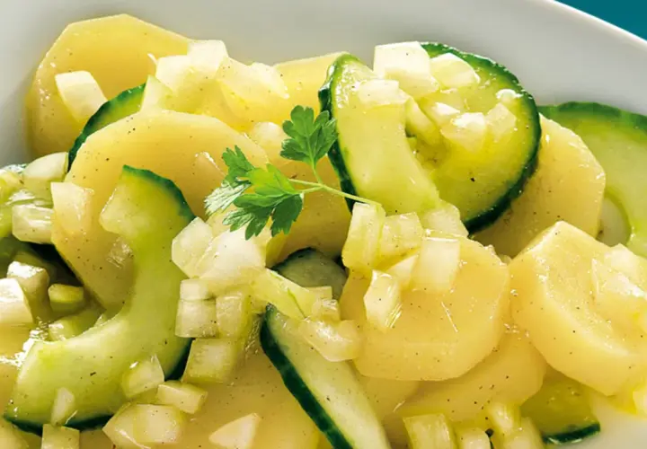 Ein appetitlicher Kartoffelsalat mit Gurken, verfeinert mit Zwiebeln und Petersilie.