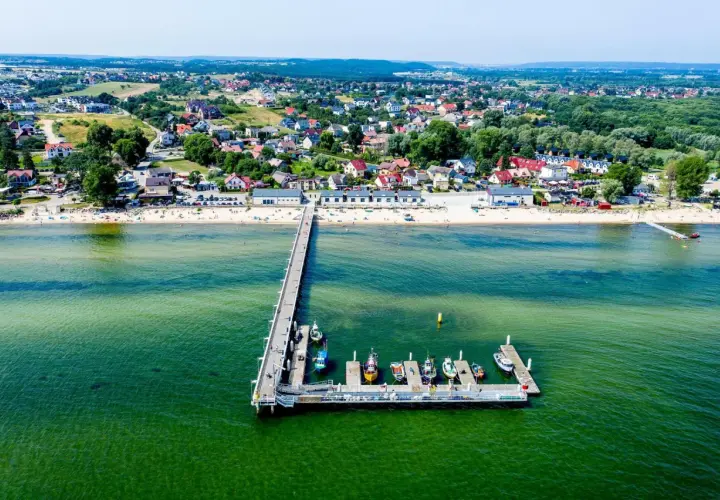 Mechelinki - warto jechać! Widok na molo, plażę i urokliwą nadmorską miejscowość.