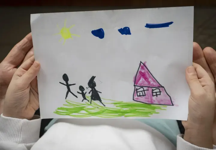 Disegni psicologia test bambini: una famiglia stilizzata cammina verso una casa rosa sotto un sole giallo e nuvole blu.