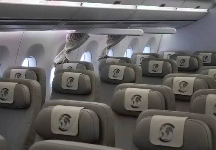 Innenansicht eines Flugzeugs mit Reihen von grauen Sitzen, die für den Bundeskanzler und seine Delegation reserviert sind. Jede Kopfstütze ziert ein Emblem mit der Weltkugel.