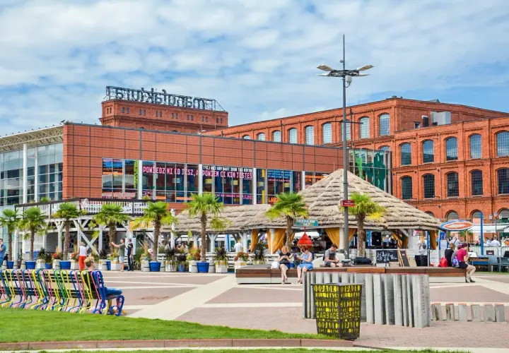Nowoczesny plac z palmami, kawiarnią i ceglanymi budynkami w Łodzi.