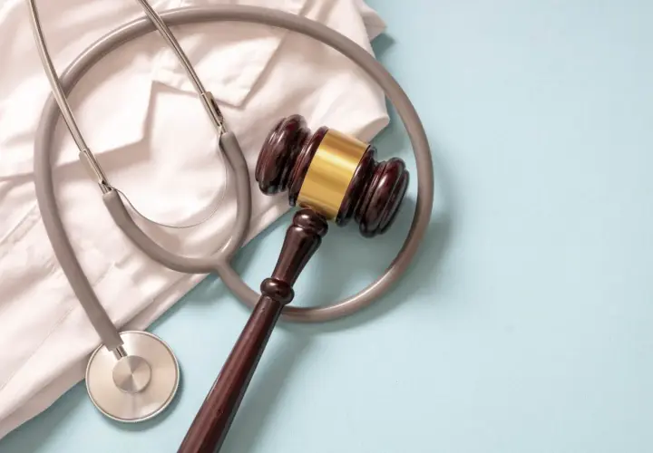 Martelletto da giudice e camice bianco con stetoscopio. Simboleggia la giustizia medica e la diagnosi sbagliata tumore.