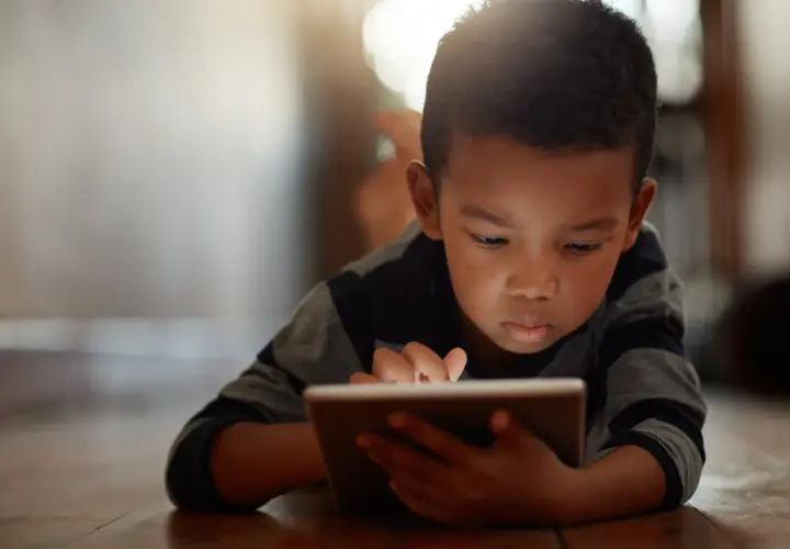 Un niño concentrado en su tablet, un ejemplo de cómo los niños introvertidos exploran mundos digitales.