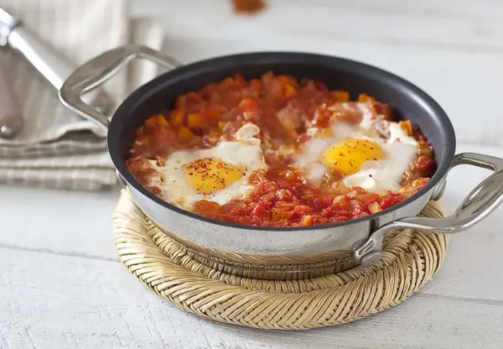 Un plat d'oeuf tomate mijoté dans une poêle, avec des poivrons et des épices. Un délice pour le petit-déjeuner.