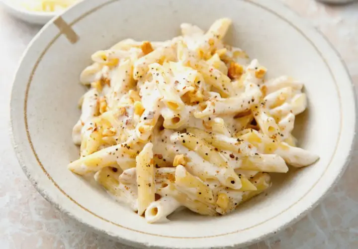 Penne w kremowym sosie z orzechami włoskimi, posypane pieprzem. Pyszne danie, które zachwyci każdego smakosza.