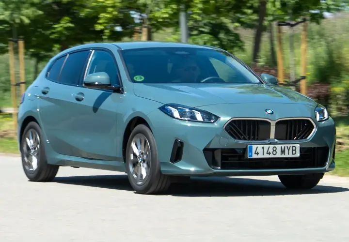 Un BMW Serie 1 gris circula por una carretera. El motor BMW 1.5 3 cilindros es eficiente, pero algunos usuarios reportan problemas.
