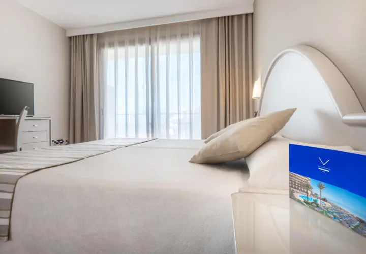 Habitación luminosa con cama doble, TV y folleto del Vik Gran Hotel Costa del Sol.