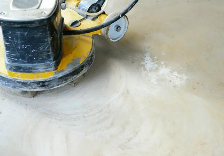 Eine Poliermaschine bearbeitet einen geschliffenen Betonboden, hinterlässt feinen Staub und glatte Spuren.