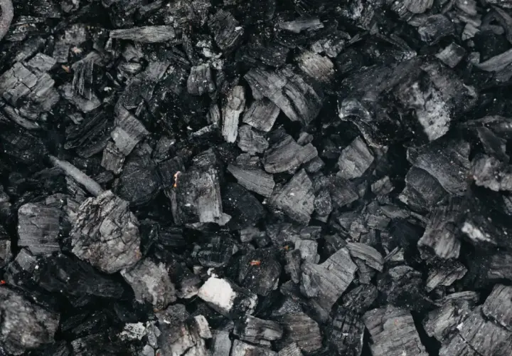 Gros plan sur des morceaux de machefer pellet, résidus noirs et gris de combustion, évoquant la chaleur d'un feu de bois.