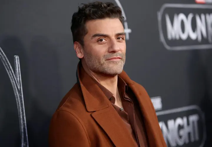 Oscar Isaac, l'attore di Moon Knight, posa con un cappotto marrone.