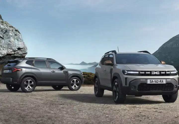Dwa nowe SUV-y Dacia Duster, idealne na wyprawy do 40 tys. zł, stoją na kamienistym podłożu w górskim krajobrazie.
