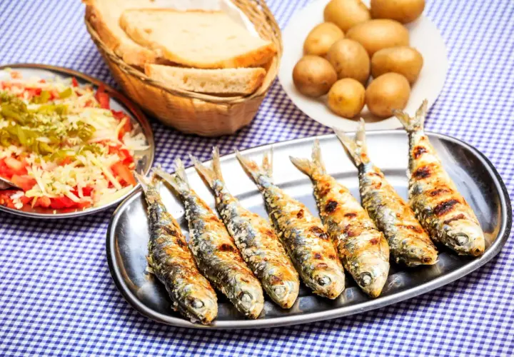Sardines grillées sur un plateau, accompagnées de pommes de terre, salade et pain. La cuisson des sardines sans odeur est un vrai délice !