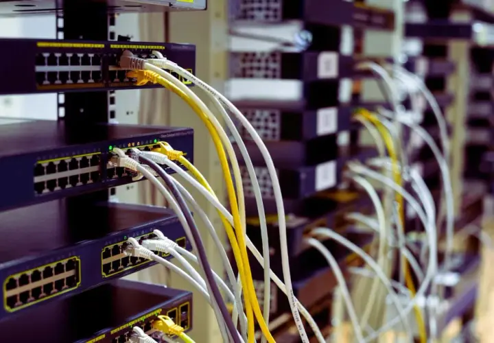 Faisceau de câblage RJ45 b, avec des câbles blancs, jaunes et gris connectés à des commutateurs réseau empilés.