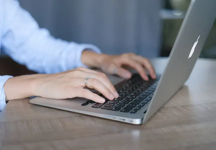Mani su tastiera di un laptop, con anello nuziale. Lavoro da remoto per ottenere myecm crediti.
