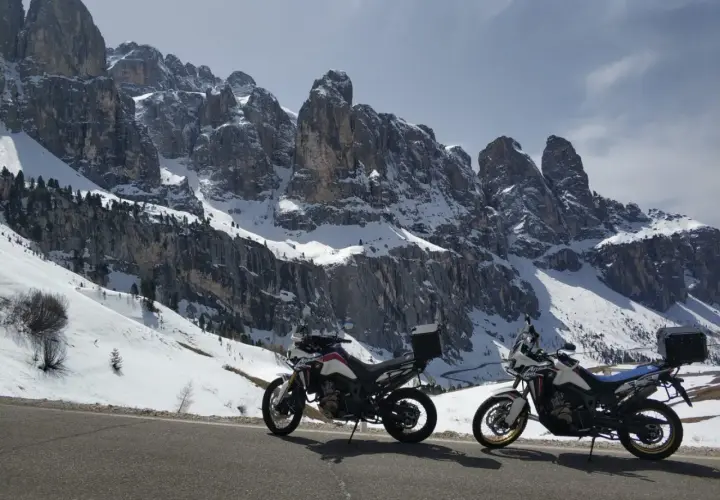 Due moto pronte per affrontare i passi bergamaschi innevati, con imponenti vette rocciose sullo sfondo.