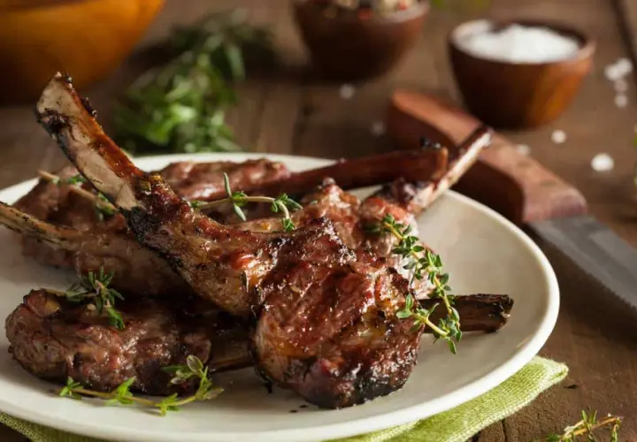 Délicieuses côtelettes d'agneau grillées, garnies de thym frais, prêtes à être dégustées.