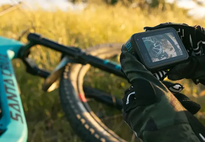 Ręce w rękawicach trzymają kamerę GoPro, gotową do nagrywania zjazdów na rowerze górskim. Niesamowite gopro zdjęcia czekają!