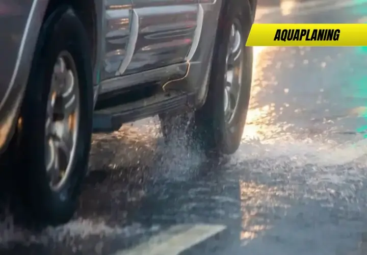 Un coche sufre aquaplaning en un día lluvioso, levantando agua al pasar.