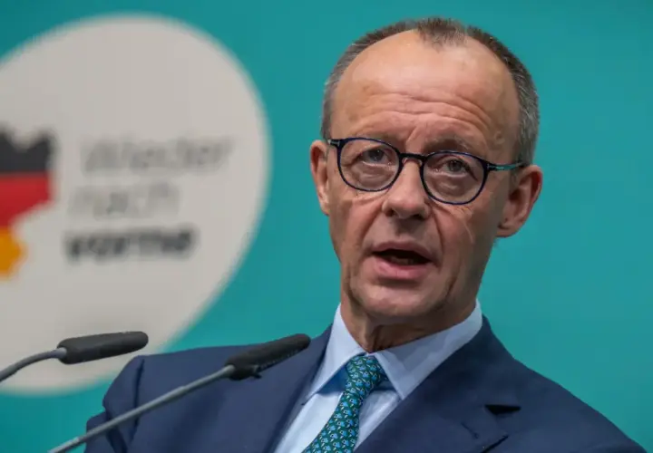 Mann mit Brille spricht ins Mikrofon. Im Hintergrund eine Deutschlandkarte mit Flaggenfarben und der Aufschrift "Wieder nach vorne". Möglicherweise im Kontext einer rtl aktuell umfrage.