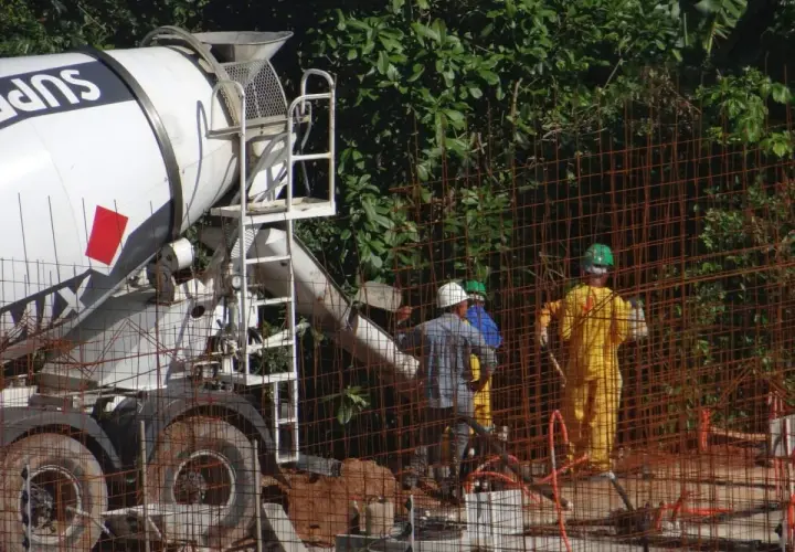 Betoniarka dostarcza beton na budowę. Zastanawiasz się, ile kosztuje metr betonu z betoniarki? Pracownicy w kaskach nadzorują rozładunek.