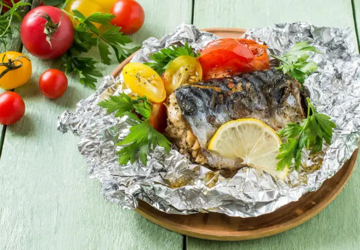 Poisson cuit dans l'aluminium, servi avec des tomates et du persil. Un délice simple et savoureux.