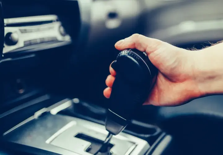 Dłoń trzymająca dźwignię zmiany biegów w samochodzie. Pytanie: czy mając prawo jazdy na automat można jeździć manualem?