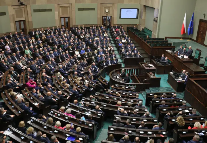 Posiedzenie Sejmu RP, wielu posłów siedzi w ławach, na mównicy przemawia mężczyzna.